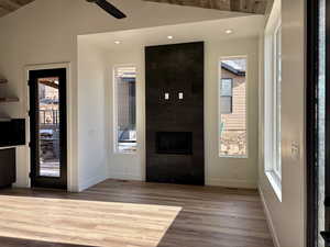 Entrance foyer featuring wood finished floors, a fireplace, ceiling fan, and lofted ceiling