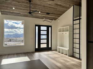 Entrance foyer with wood finished floors, vaulted ceiling, wooden ceiling, a mountain view, and ceiling fan