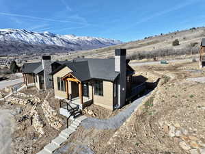 View of front of house featuring a chimney, a mountain view, and a shingled roof