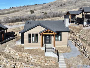 View of front of house featuring a shingled roof, a chimney, and a mountain view