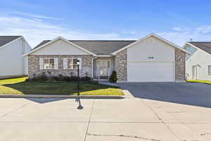 Ranch-style house with a front lawn, concrete driveway, brick siding, an attached garage, and a shingled roof