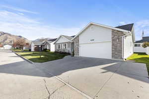 Ranch-style home with concrete driveway, a front yard, a residential view, a garage, and brick siding