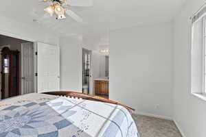 Bedroom featuring ensuite bathroom, light carpet, and a ceiling fan