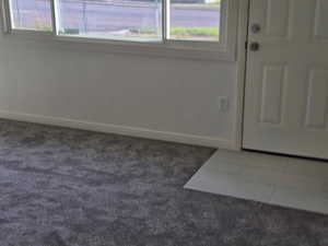 Foyer featuring baseboards and dark colored carpet