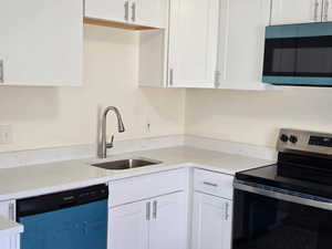 Kitchen featuring stainless steel appliances, white cabinets, and light stone countertops