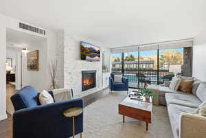 Living room featuring a fireplace, expansive windows, and wood finished floors