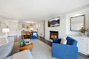 Living room with a stone fireplace and dark wood finished floors
