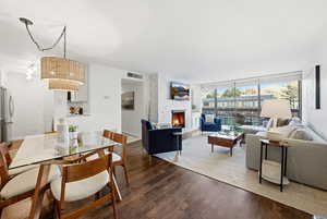 Dining room with a large fireplace, wood finished floors, and a wall of windows