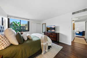 Bedroom with dark wood-style flooring and a closet