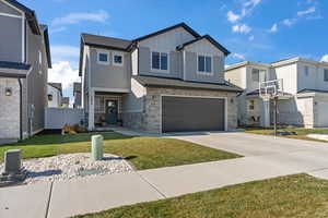 Craftsman house with board and batten siding, stone siding, driveway, a garage, and a residential view