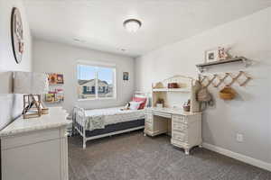 Bedroom featuring dark colored carpet and a textured ceiling