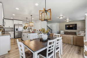 Dining space with a chandelier, stairway, light wood-type flooring, and recessed lighting