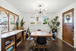 Dining room featuring a textured ceiling, dark wood finished floors, and a chandelier