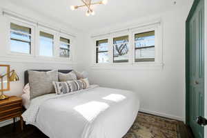 Bedroom with wood finished floors, a chandelier, and multiple windows