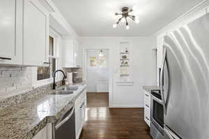 Kitchen featuring appliances with stainless steel finishes, white cabinets, dark wood finished floors, and light stone countertops