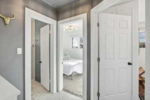 Corridor with a chandelier and light marble finish floors