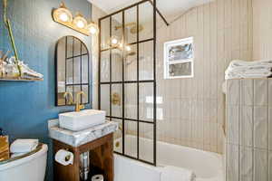 Bathroom with a textured wall, shower / washtub combination, and vanity