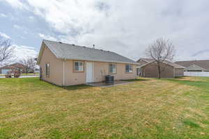 Back of property featuring a patio area, a yard, a shingled roof, and stucco siding