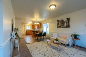 Living area featuring a textured ceiling, a chandelier, and light colored carpet
