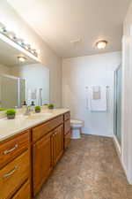 Full bathroom featuring a shower stall, stone finish flooring, vanity, and a textured ceiling