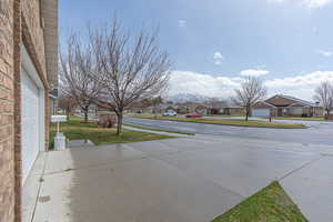 View of green lawn with a residential view, driveway, and a garage