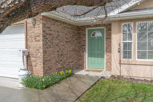 Doorway to property with a garage and brick siding