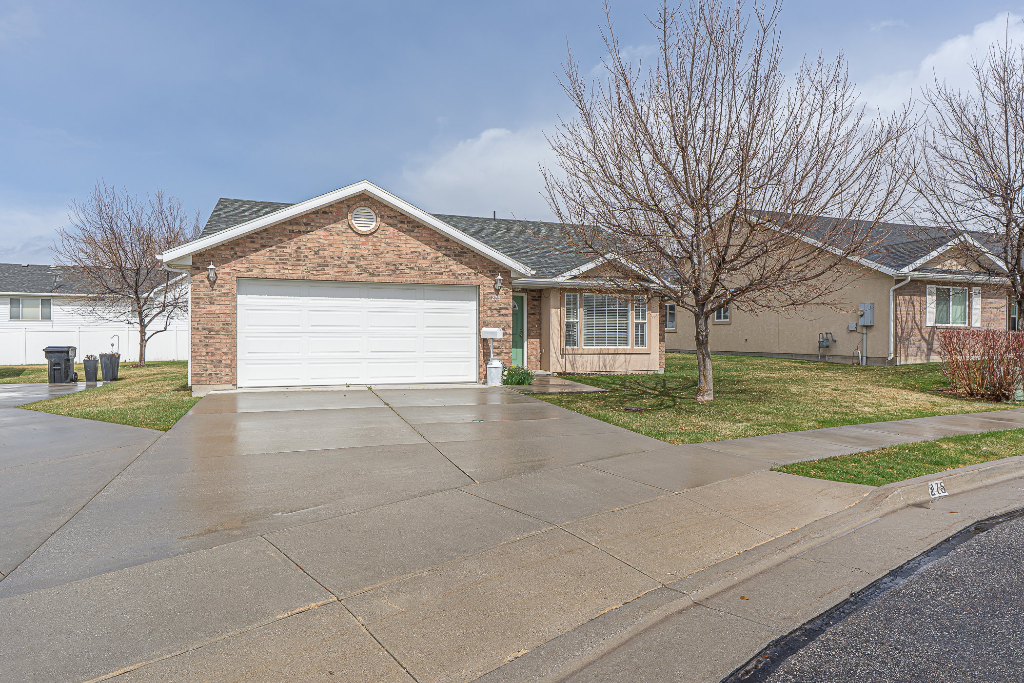 Single story home with a front lawn, driveway, brick siding, and a shingled roof