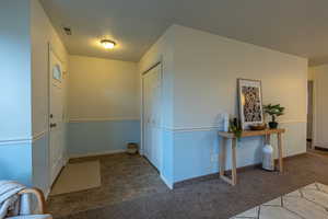 Entrance foyer with dark colored carpet and stone finish flooring