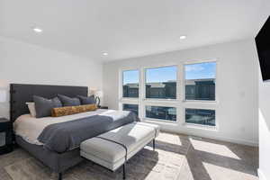 Bedroom with light colored carpet, multiple windows, and recessed lighting