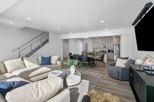 Living area with light wood-style flooring, recessed lighting, and stairs