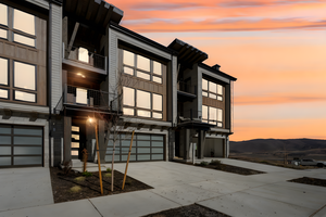 Contemporary home with a balcony, stone siding, driveway, and an attached garage