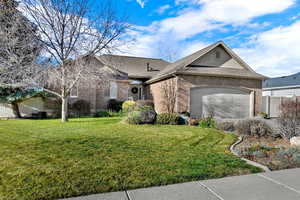 View of front of house with brick siding, a front lawn, a garage, and roof with shingles
