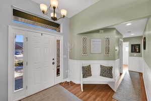 Foyer entrance featuring wainscoting, wood finished floors, a chandelier, and a decorative wall