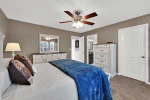 Bedroom featuring light carpet, ceiling fan, and ensuite bath