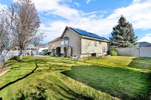 View of property exterior featuring a fenced backyard, a gate, roof mounted solar panels, and a patio area