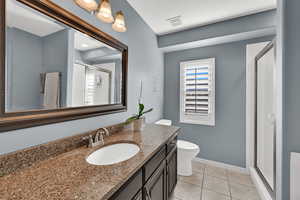 Bathroom with a shower stall, vanity, and light tile patterned floors