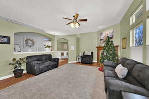 Living room featuring arched walkways, a ceiling fan, wood finished floors, and a textured ceiling