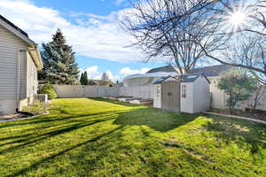 Fenced backyard featuring a storage shed and a gate