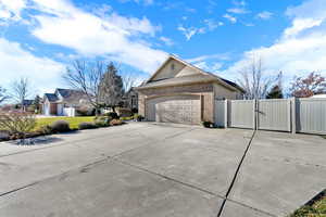 View of property exterior featuring a gate, brick siding, driveway, and a garage