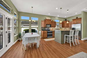 Kitchen featuring brown cabinetry, a kitchen breakfast bar, stainless steel appliances, pendant lighting, and a chandelier