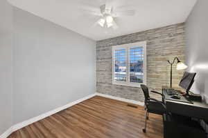 Office space with wood finished floors, an accent wall, wood walls, and a ceiling fan