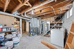 Unfinished basement featuring washer / clothes dryer, strapped water heater, and heating unit