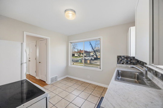 Kitchen featuring electric range oven, light countertops, freestanding refrigerator, light tile patterned floors, and white cabinetry