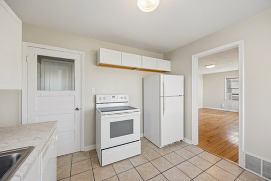 Kitchen with white cabinetry, white appliances, light countertops, and light tile patterned flooring