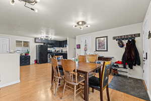 Dining area with a textured ceiling and light wood-type flooring