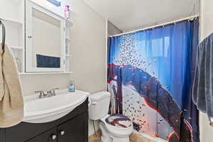 Full bath with a shower with curtain, vanity, a textured ceiling, and a textured wall