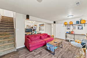 Living room featuring wood finished floors, a textured ceiling, stairway, and washer / clothes dryer
