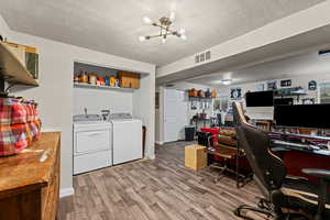 Office area featuring a textured ceiling, light wood-style floors, washer and dryer, and a chandelier
