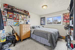 Bedroom featuring a textured ceiling and light carpet