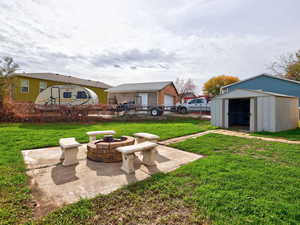 View of yard with an outdoor fire pit, a patio area, and a storage unit